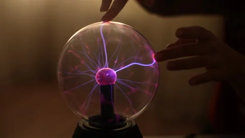 Close-up hands of unrecognizable woman touching electric plasma ball with Stock Footage 276546339
