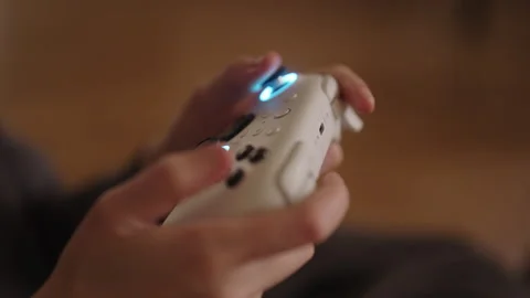 Close-up hands of unrecognizable woman using modern gaming controller with Stock Footage 320288243