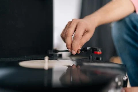 Close-up hands of unrecognizable young man adjusting head old record player and Stock Photos