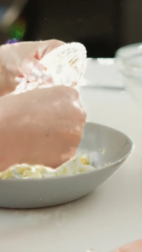 Close up of Hands Unwrapping Small Netted Object Over Chopped Egg Salad in Soft Stock Footage 346795047