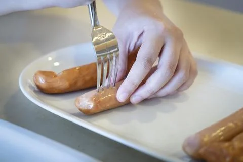 Close-up hands use fork puncturing homemade sausage. Foto stock