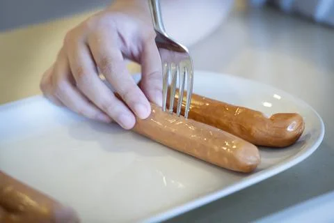 Close-up hands use fork puncturing homemade sausage. Stock-Fotos