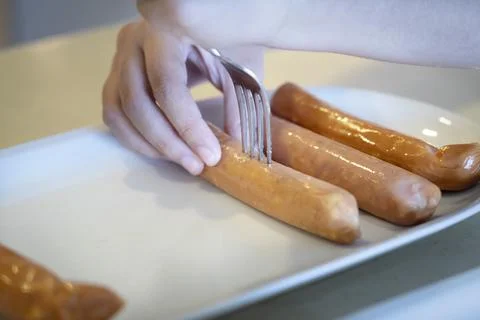 Close-up hands use fork puncturing homemade sausage. Foto stock