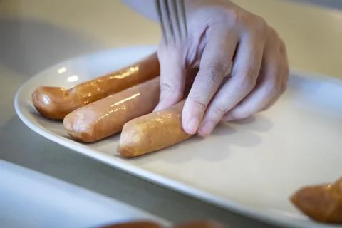 Close-up hands use fork puncturing homemade sausage. Stock Photos