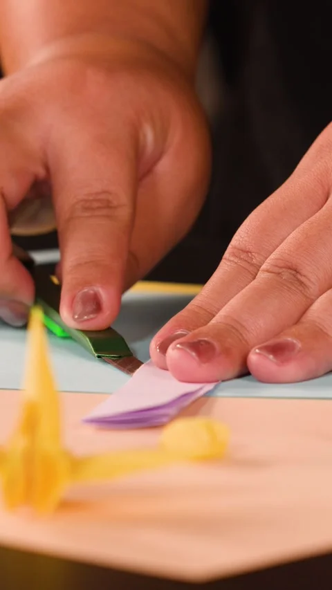 Close Up of Hands Using a Bone Folder Tool on Origami Paper Stock Footage 327830705