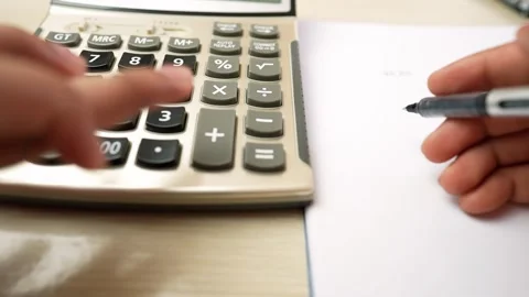 Close-up of hands using a calculator and writing on paper Stock Footage 318578192