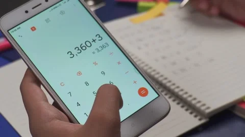 Close up of hands using a calculator on a phone to do math Stock Footage 276932907
