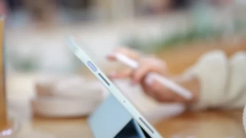 Close-up of hands using digital tablet and stylus while seated indoors Video stock 346236844