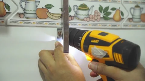 Close up of hands using an electric drill driver to install a metal bracket on a Stock Footage 346644194