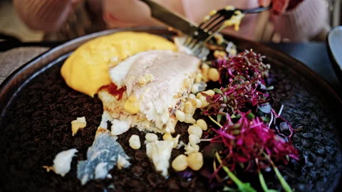 Close up of hands using a fork and knife to cut into a gourmet seared fish Stock Footage 335346216