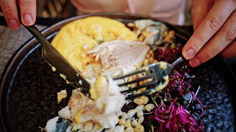 Close up of hands using a fork and knife to cut into a gourmet seared fish Vidéo 335346502