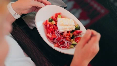 Close up of hands using fork to eat fresh greek salad with feta cheese. Vídeos de archivo 340844882
