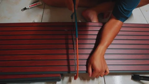 Close-up of Hands Using Hand Saw to Cut Wood-Look PVC Profile for Home Stock Footage 333320445