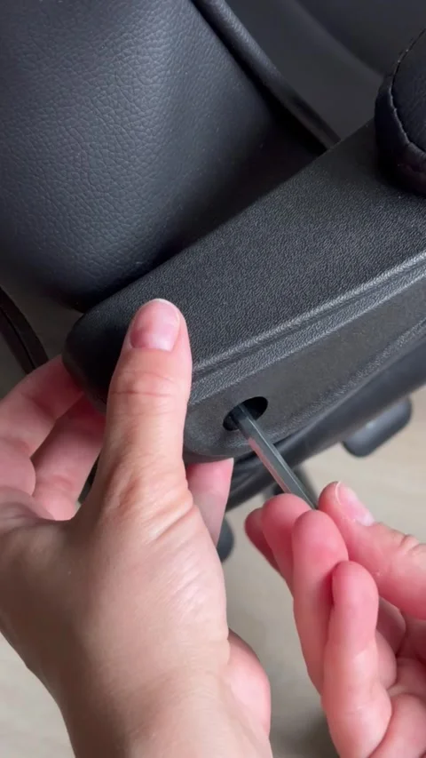 Close-up of hands using a hex key to disassemble or loosen the armrest Stock Footage 315563988