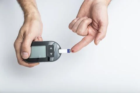 Close up of hands using lancet on finger to check blood sugar level by Glucose Stock Photos