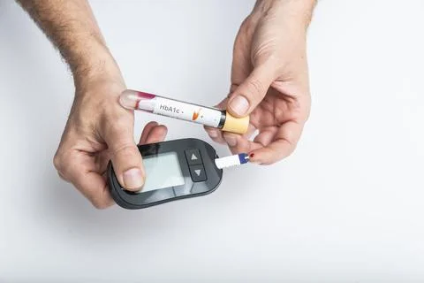 Close up of hands using lancet on finger to check blood sugar level by Glucose Stock Photos