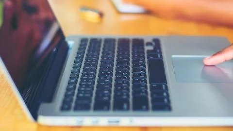 Close up of hands using a laptop keyboard and trackpad Stock Photos