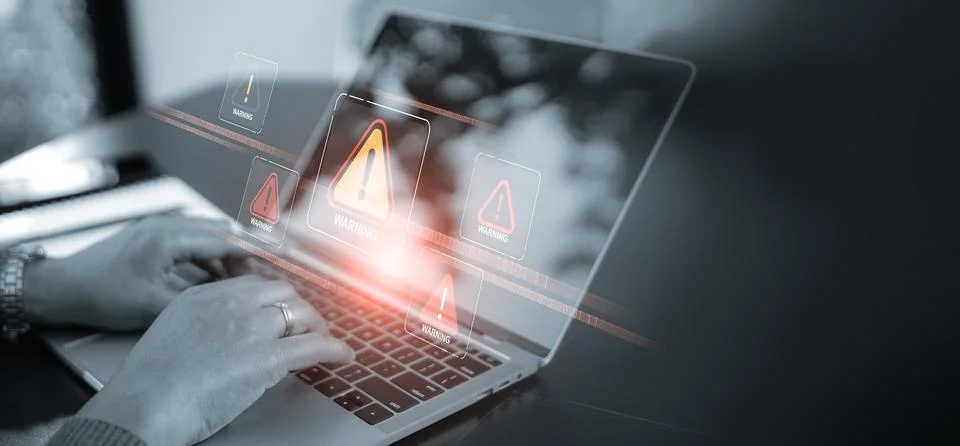 A close up of hands using a laptop with multiple red warning signs and aler.. Stock Photos