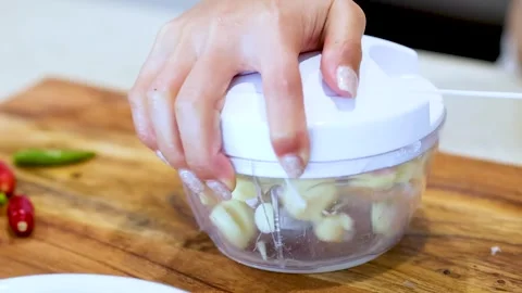 Close Up of Hands Using Manual Pull String Food Chopper for Garlic Stock Footage 329537202