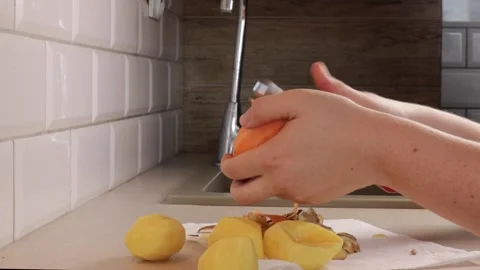 Close-up of hands using a metal vegetable peeler to remove the skin from a .. Stock Footage 320955719