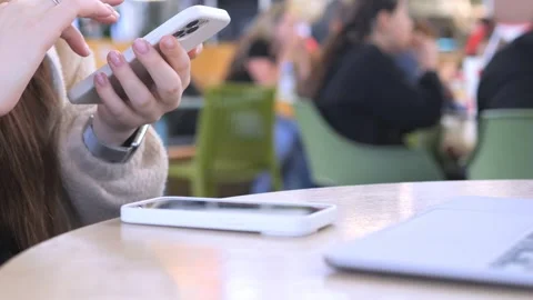Close-up of hands using mobile phone in public cafe Stock Footage 343573545