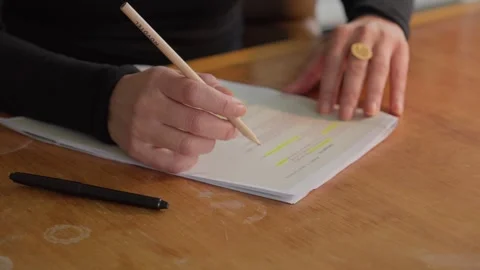 A close-up of hands using a pencil and highlighter to review important Stock Footage 335964772