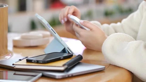 Close-up hands using phone with tablet and phone resting nearby Video stock 345708177