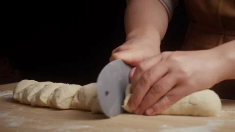 Close-up of hands using a pizza cutter to slice freshly rolled dough into equal Vidéo 341339830