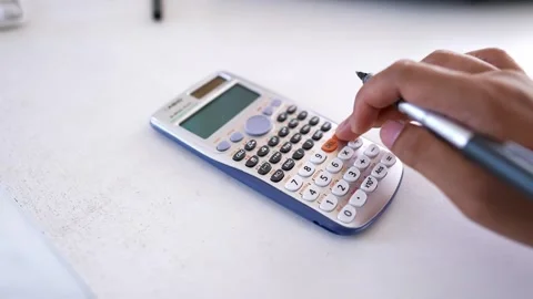 Close-up of hands using a scientific calculator on a white surface Stock Footage 316744978