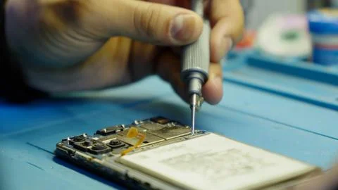 Close up of hands using a screwdriver to fix a mobile phone. Stock Photos