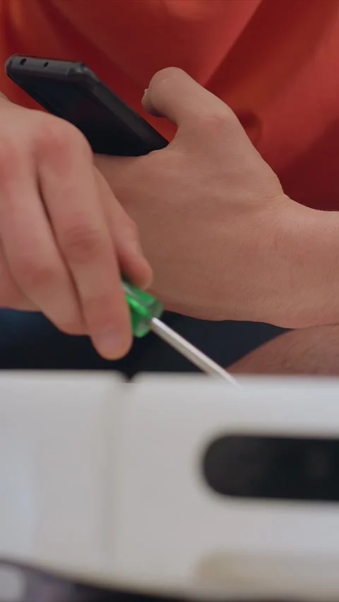 Close up of hands using screwdriver to repair electronic device showing Stock Footage 346786887