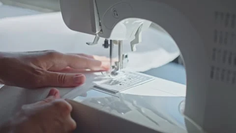 Close up of hands using sewing machine to stitch white fabric Stock Footage 314795690