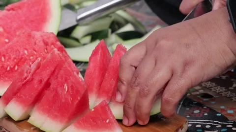 Close up of hands using a sharp knife to slice fresh ripe red watermelon. Video stock 329194898