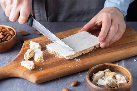 Close-up of hands using a sharp knife to cut a piece of traditional hard wh.. Stock Photos
