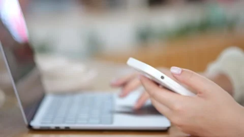 Close-up of hands using smartphone beside open laptop Stock Footage 345676306