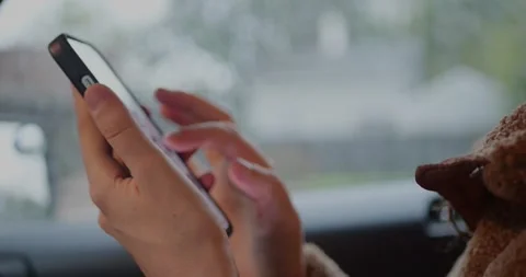 Close-up of hands using a smartphone in a car with soft daylight through... Vidéo 319882326