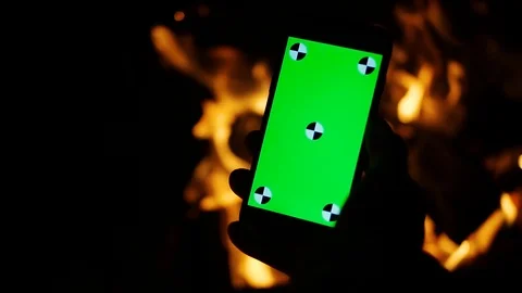 Close up hands using smartphone with green screen by the burning fireplace cozy Stock Footage 105205100