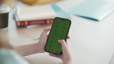 Close up of hands using smartphone with green screen on wooden desk during study Stock Footage 341337191