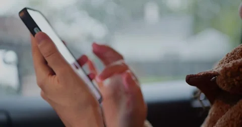 Close-up of hands using a smartphone inside car, tapping the... Stock Footage 319882320