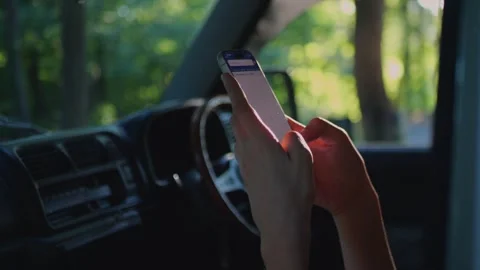Close-up of hands using a smartphone inside a car with soft forest light... Stock Footage 341613123