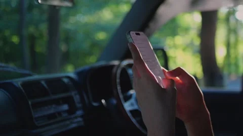 Close-up of hands using a smartphone inside a car with blurred forest... Stock Footage 341613128