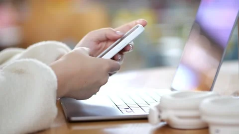 Close-up of hands using smartphone near laptop Stock Footage 347662237