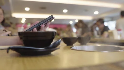 Close-up of hands using a smartphone at a restaurant table with black bowls.. Vídeos de archivo 335005921