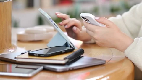 Close-up of hands using smartphone with tablet and phones on table Stock Footage 346155484