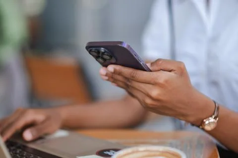 Close up of hands using smartphone while working on laptop with coffee on t.. Stock Photos