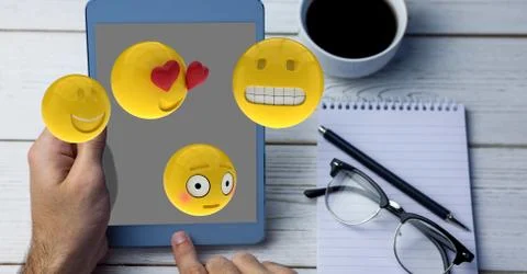 Close-up of hands using tablet PC while emojis flying over table Stock Photos