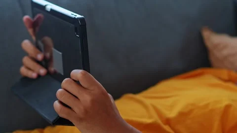 Close-up of hands using tablet screen while lying and relaxing on sofa Stock Footage 346029561