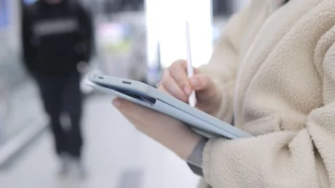 Close-up of hands using tablet with stylus in well-lit space Stock Footage 347348376