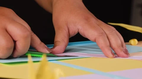 Close Up of Hands Using a Utility Knife to Cut Colored Paper Stock Footage 327121118