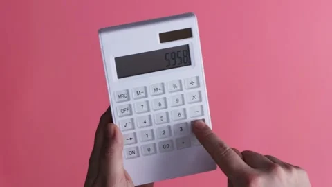 Close-up of hands using a white calculator with a pink background Stock Footage 339189334